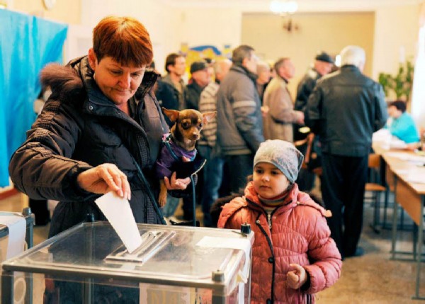 A woman casts her vote while holding her dog at a polling station on March 16, 2014 in Simferopol